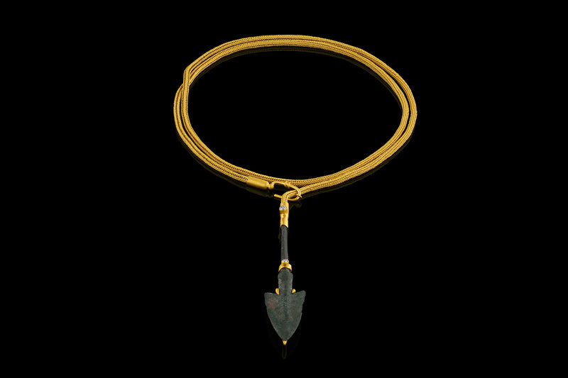 Persian bronze arrowhead (c. 1200-1800 BCE) in a modern gold frame accented with diamonds on a handwoven gold chain.