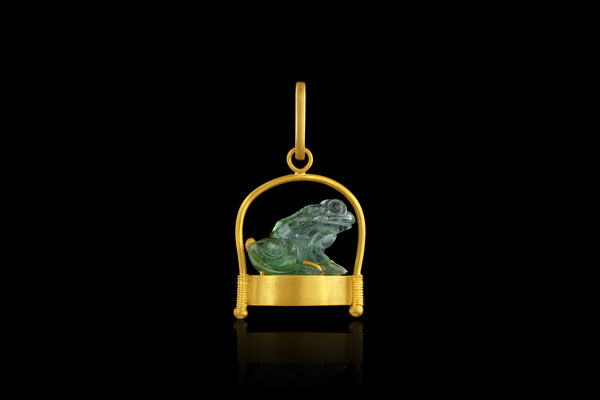 Craved green tourmaline frog pendant on gold base and wire frame. Side view.