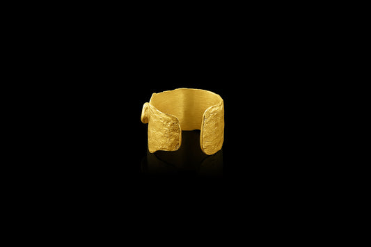 An ear cuff formed from a hammered sheet of gold, accented with a diamond, featuring an organic edge inspired by papyrus, the reed paper used by the ancient Egyptians.