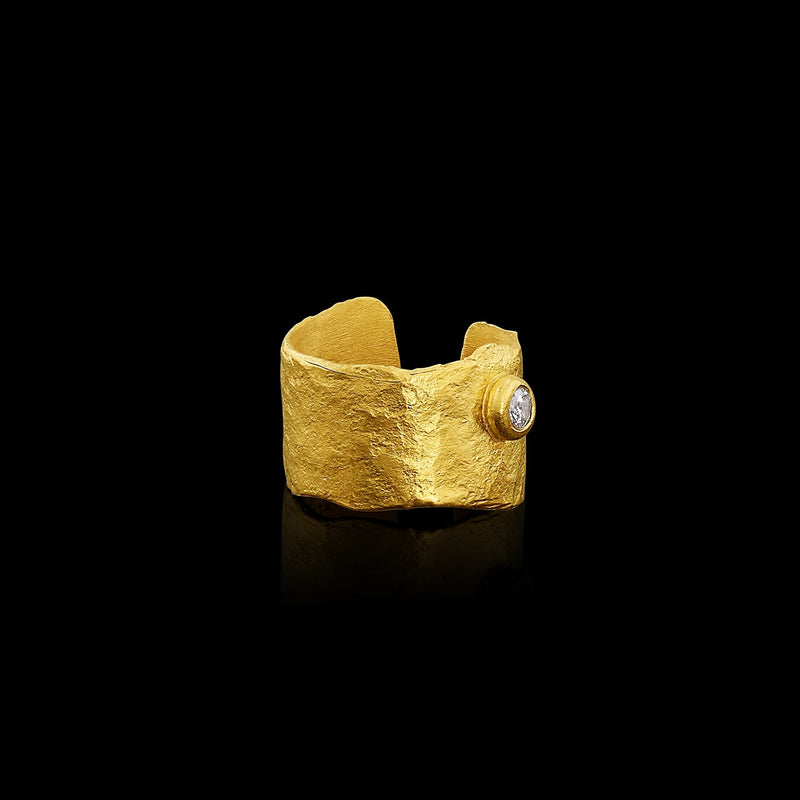 An ear cuff formed from a hammered sheet of gold, accented with a diamond, featuring an organic edge inspired by papyrus, the reed paper used by the ancient Egyptians.