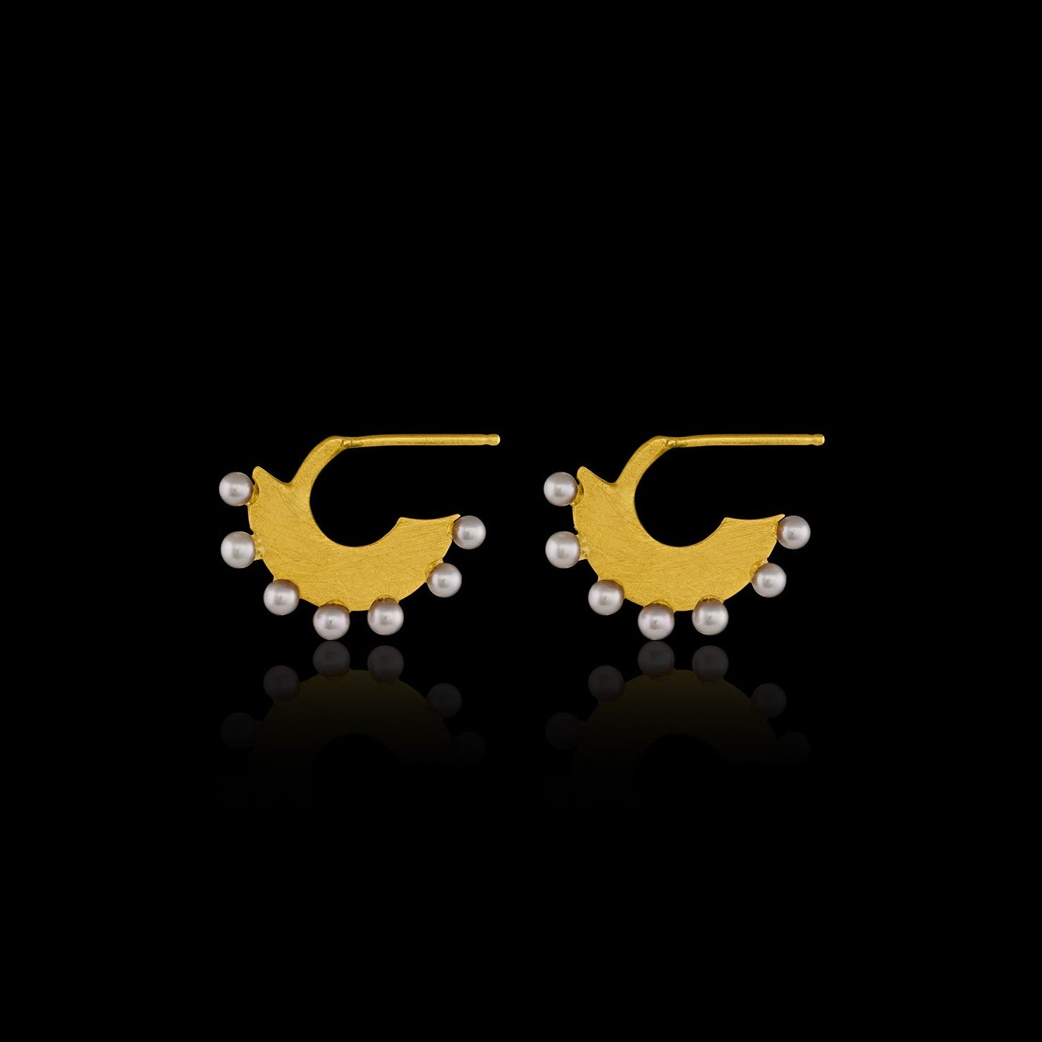 Flat gold huggie hoop earring with seven white pearls along the edge.  Side view. 