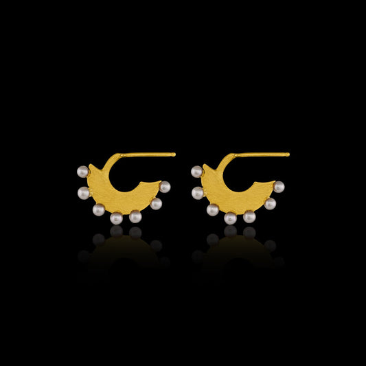 Flat gold huggie hoop earring with seven white pearls along the edge.  Side view. 