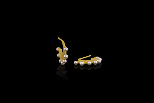 Flat gold huggie hoop earring with seven white pearls along the edge.  Standing view.