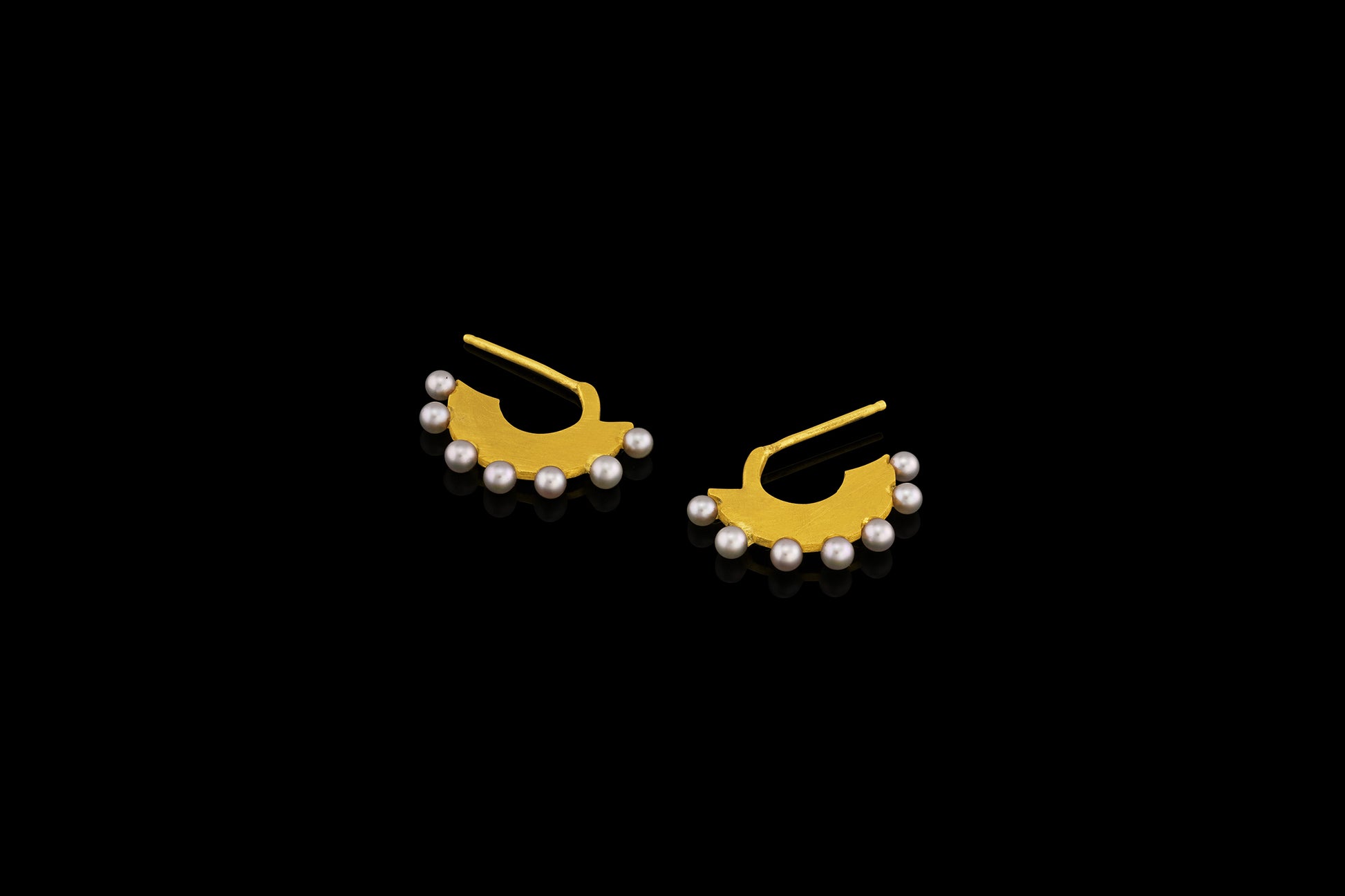 Flat gold huggie hoop earring with seven white pearls along the edge.  