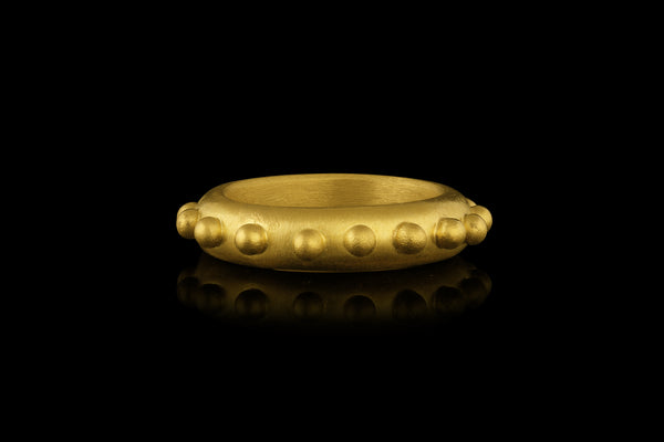A 22k gold band ring accented with gold spheres - side view